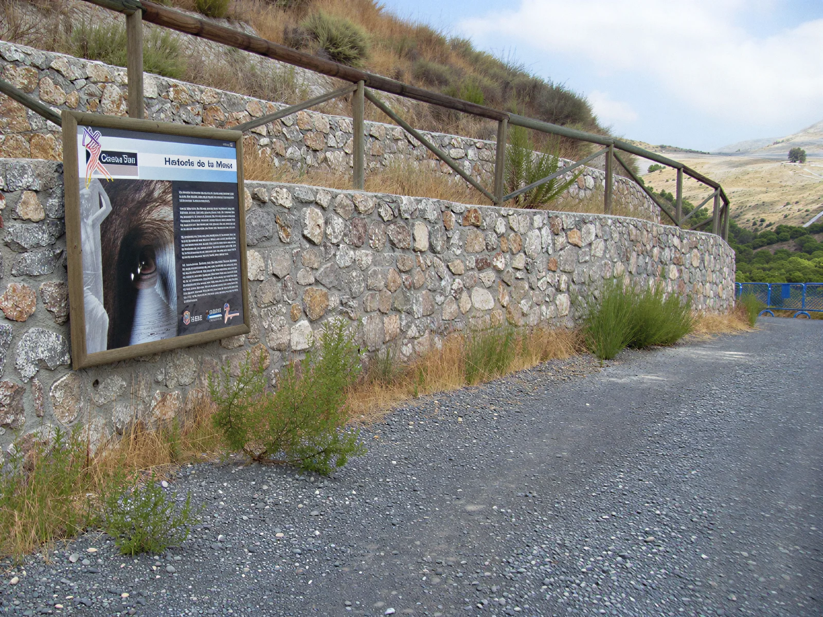Camino exterior, muro de piedra y panel interpretativo del Cerro del Toro